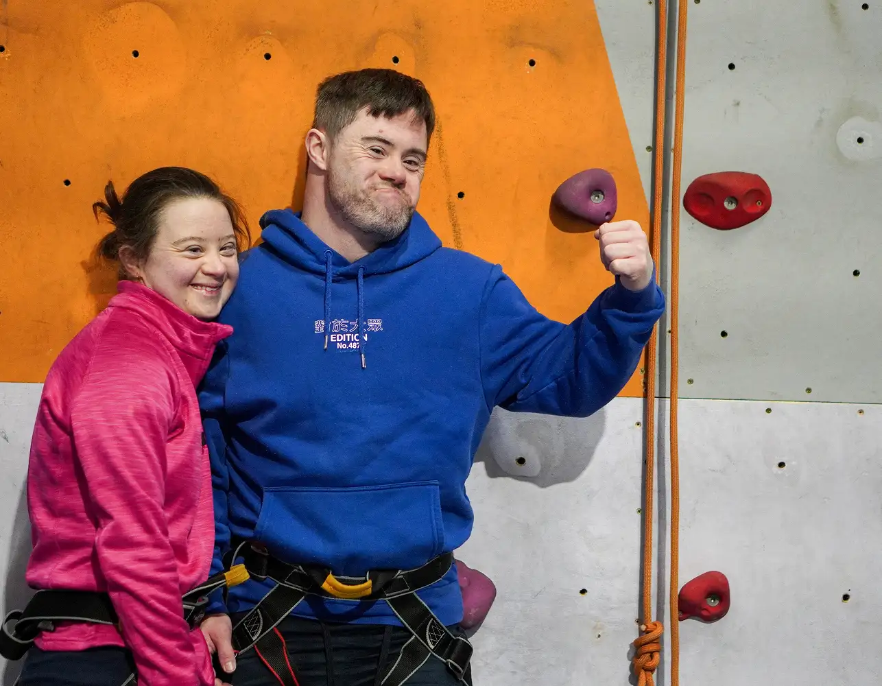 Young people posing in front of a rock climbing wall